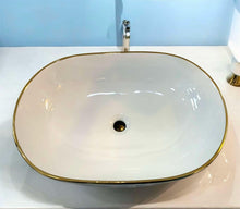 Load image into Gallery viewer, Oval Tabletop Wash Basin with Pristine White Interior Gleaming Gold Base and Refined Gold Striped Accents