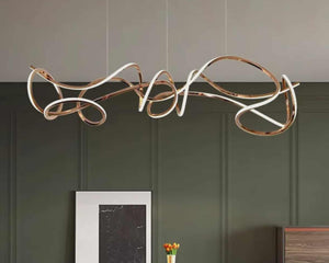 Modern pendant light fixture hanging above a dining table with a green wall background.