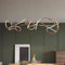 Modern pendant light fixture hanging above a dining table with a green wall background.