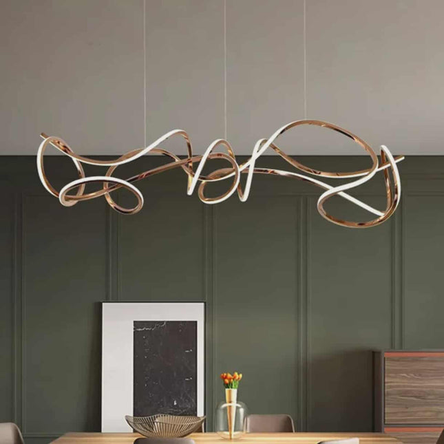 Modern pendant light fixture hanging above a dining table with a green wall background.