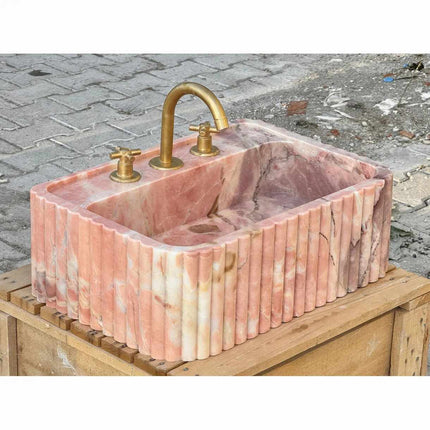 Lavabo mural en marbre rose naturel pour salle de bain, avec lave-mains intégré.