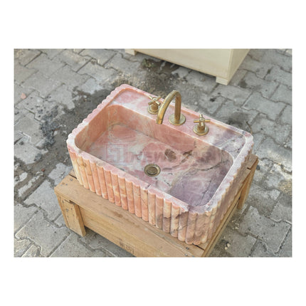 Lavabo mural en marbre rose naturel pour salle de bain, avec lave-mains intégré.