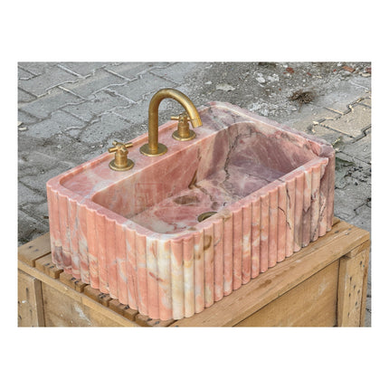 Lavabo mural en marbre rose naturel pour salle de bain, avec lave-mains intégré.
