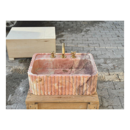 Lavabo mural en marbre rose naturel pour salle de bain, avec lave-mains intégré.