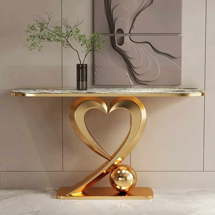 Decorative console table with gold heart-shaped base and marble top in a room setting.