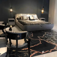 Load image into Gallery viewer, Modern Luxury Bedroom with Zebra-Print Upholstered Bed, High-Gloss Black and Gold Accented Chairs, Velvet and Silk Bedding, Custom Abstract Rug, and Elegant Pendant Lighting
