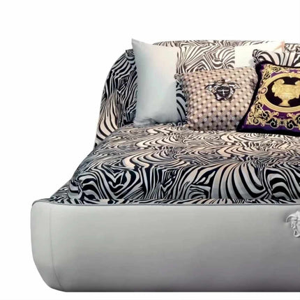 Modernes Luxusschlafzimmer mit Bett im Zebra-Print, hochglänzenden, schwarz-goldenen Sesseln, Bettwäsche aus Samt und Seide, maßgefertigtem abstrakten Teppich und eleganter Pendelleuchte