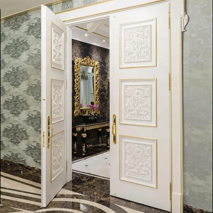 Decorative white doors with gold accents open to reveal a room with a mirror and floral arrangement.