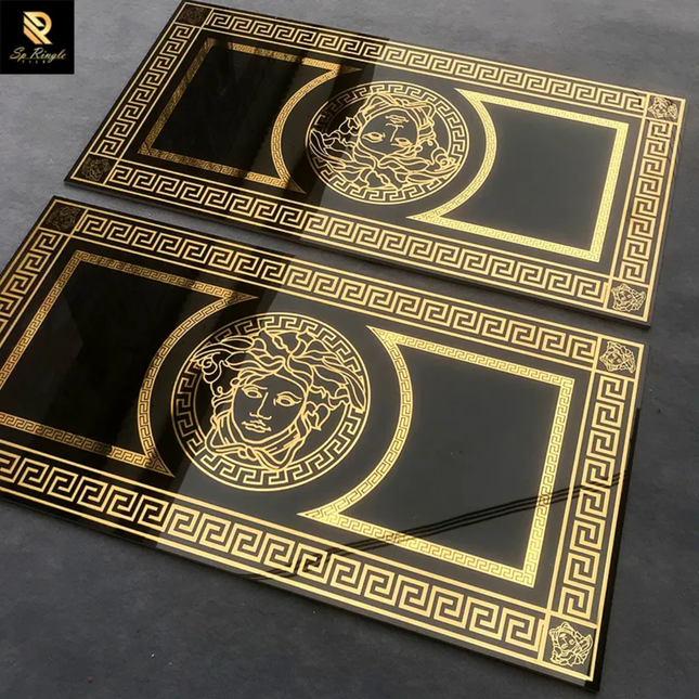 Two black and gold decorative plates with a central face design on a dark surface.
