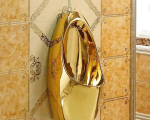 Gold-colored urinal mounted on a tiled wall.