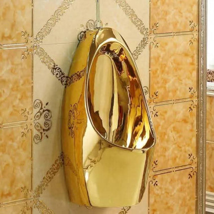Gold-colored urinal mounted on a tiled wall.