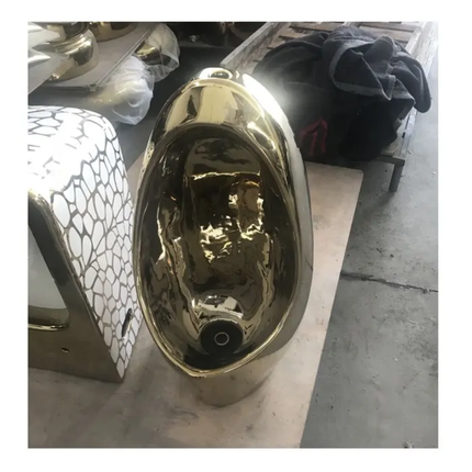 Gold metallic vase on a concrete floor with other decorative items in the background