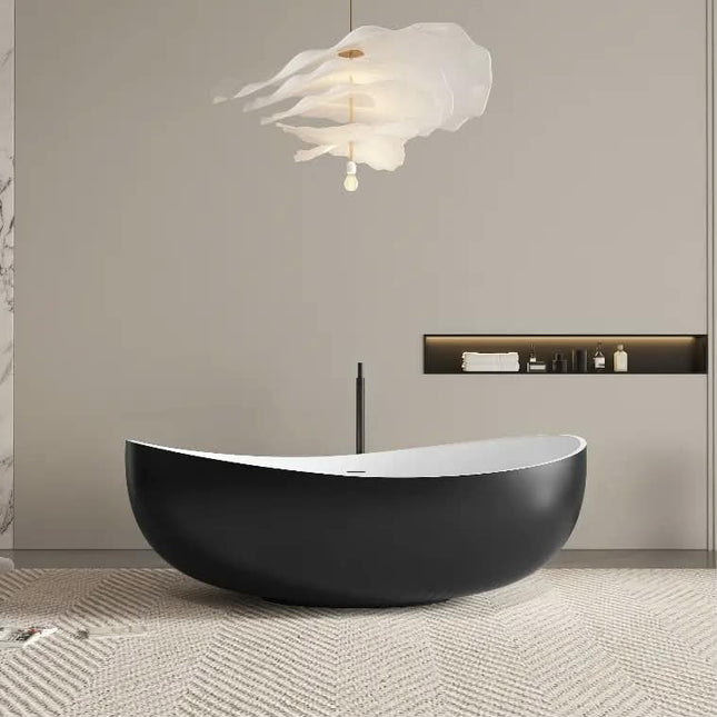 A modern freestanding oval bathtub in matte black with a white interior, set in a minimalist bathroom with a sculptural white cloud-shaped pendant light and a built-in shelf.
