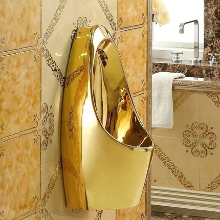 Gold urinal in a luxurious bathroom setting with ornate tiles and a mirror.