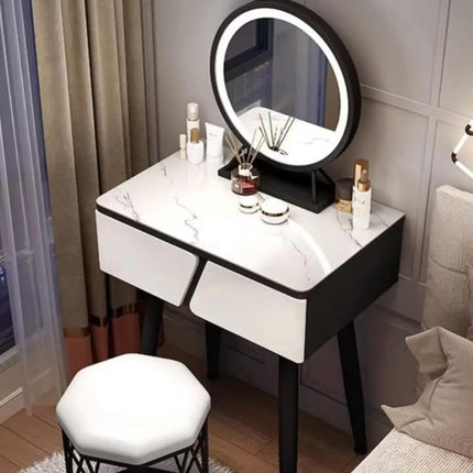 A modern vanity table with a white marble-patterned top, black frame, and built-in LED ring light, shown in a bedroom setting with a matching white stool.