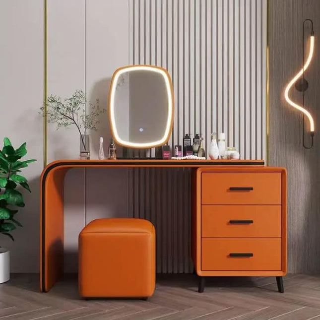 An orange vanity desk set with a built-in oval mirror, three drawers, and a matching orange stool in a modern styled room.