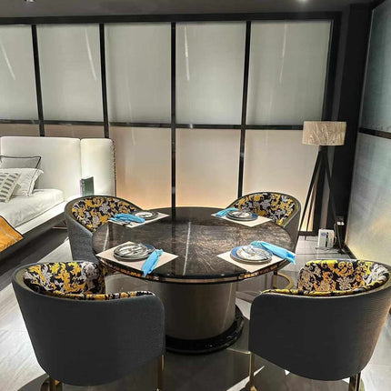 Black Round Dining Table with Black Marble Top Stainless Steel , Marble ,Leather with Gold Accents and Luxurious Upholstered Chairs Featuring Intricate Black and Gold Patterned Fabric