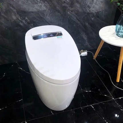 White electronic toilet seat on a black marble floor with a small table in the background.