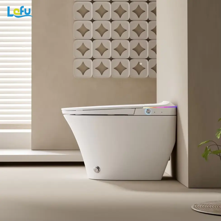 Modern toilet bowl in a bathroom setting with decorative wall art and plant.