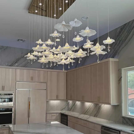 Modern kitchen with a large chandelier, wooden cabinets, and marble countertops.