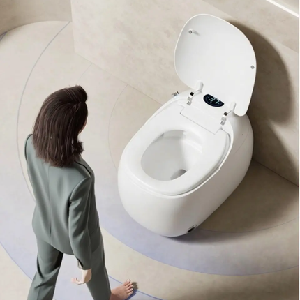 Person standing next to a modern white toilet in a minimalistic bathroom.