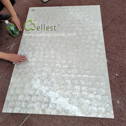 Person handling a large sheet of stone material with Weillest branding on a textured floor.