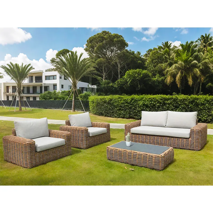 Outdoor patio furniture set with white cushions on a grassy area with palm trees and a building in the background.