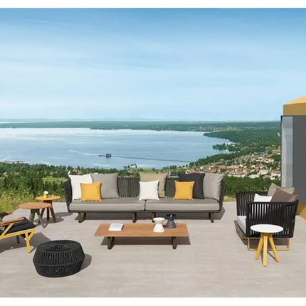 Outdoor patio set with furniture on a deck overlooking a scenic view of water and trees.