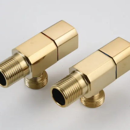 Two gold brass plumbing valves on a white background