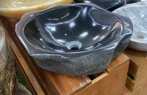 Dark Natural Marble Stone Basin Appearing to Flow from Solid Rock, Its Smooth Interior Beckoning the Touch