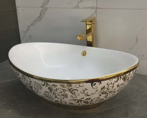 Decorative bathroom sink with gold accents and a matching faucet.