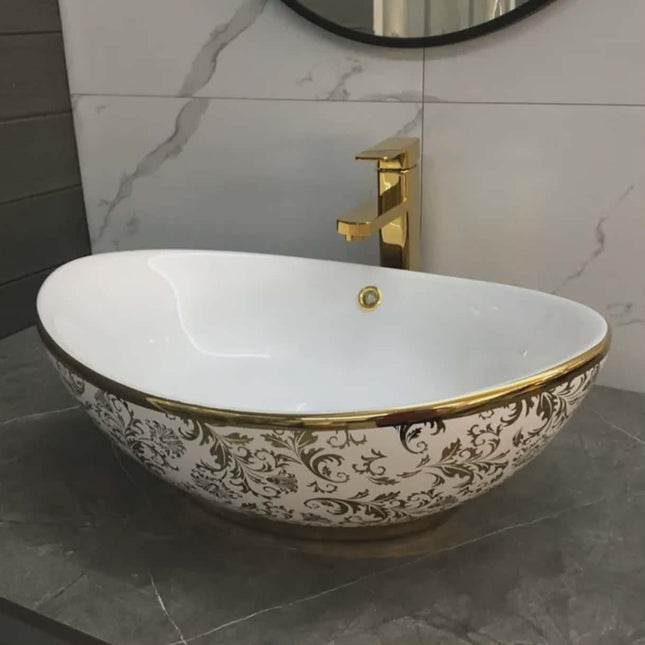 Decorative bathroom sink with gold accents and a matching faucet.