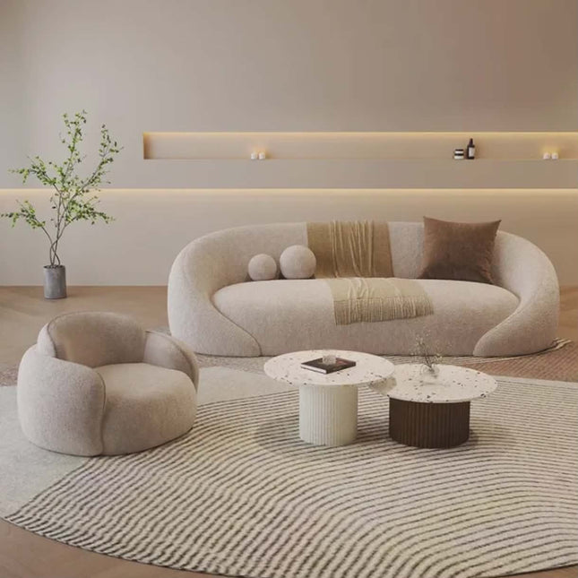 Modern living room with a curved beige sofa, armchair, and coffee table.
