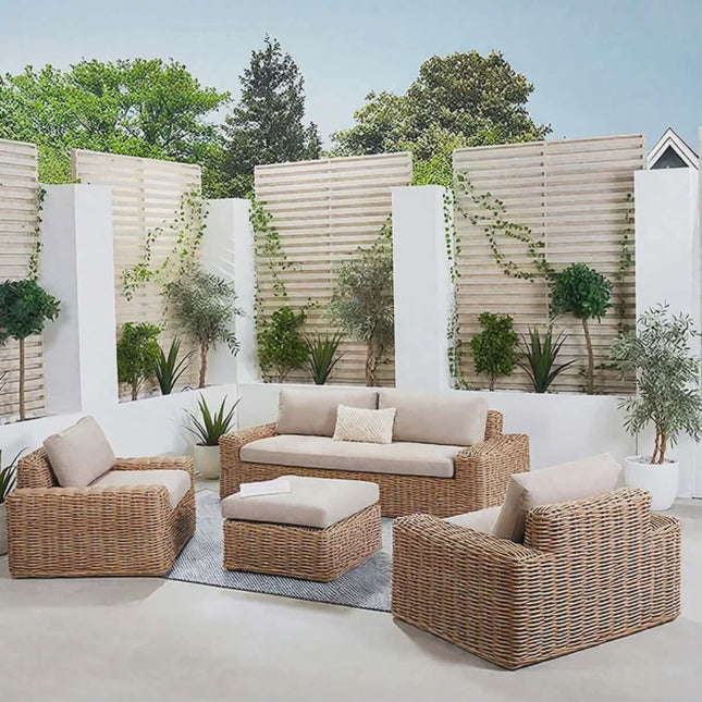 Outdoor patio set with wicker furniture and beige cushions in a garden setting.