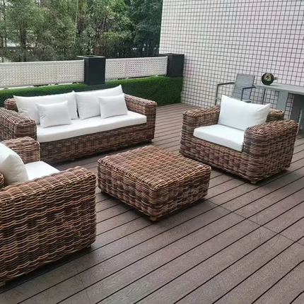 Wicker outdoor furniture set with white cushions on a wooden deck.