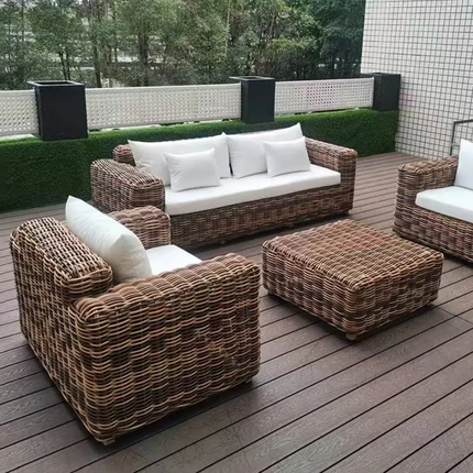 Wicker outdoor furniture set with white cushions on a wooden deck.