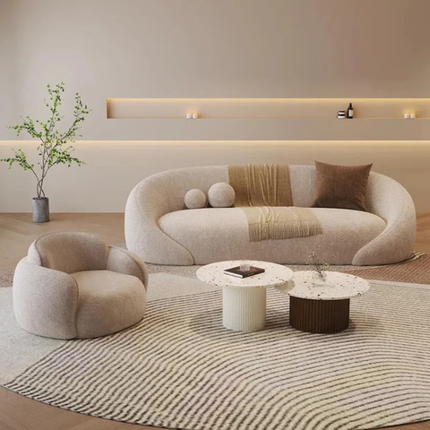 Modern living room with a curved beige sofa, armchair, and coffee table.