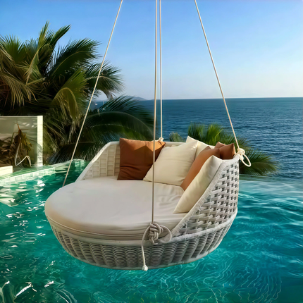 White wicker swing with cushions by a pool with ocean view