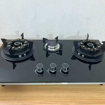 Black gas stove with three burners on a wooden surface.