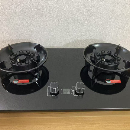Black gas stove with two burners on a wooden surface.