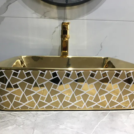 Gold mosaic patterned sink with geometric design on a tiled wall background