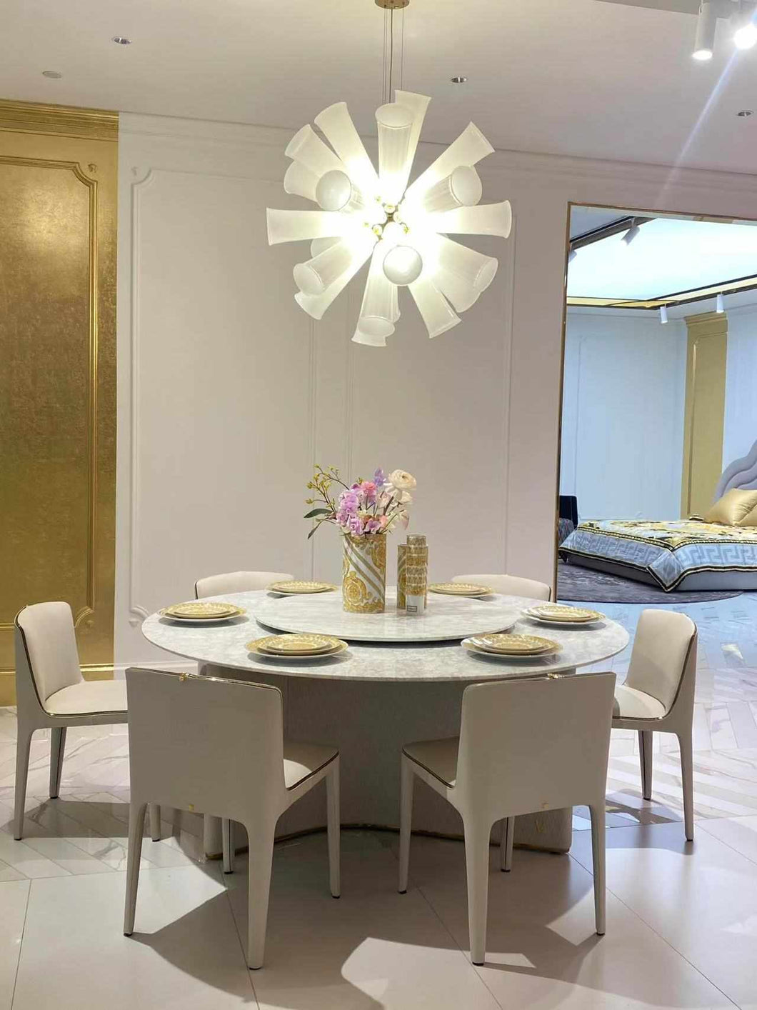 Elegant Modern Dining Room Featuring a Round Marble Table and  White Upholstered Chairs Gold-Accented Dinnerware and Luxurious