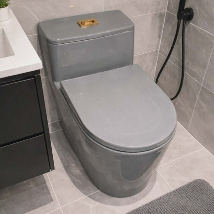 Gray toilet in a bathroom with tiled walls and a shower head.