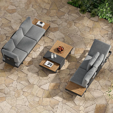 Outdoor patio furniture set with gray cushions on a stone patio.
