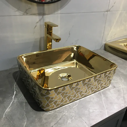 Gold-colored sink with geometric pattern on a marble countertop