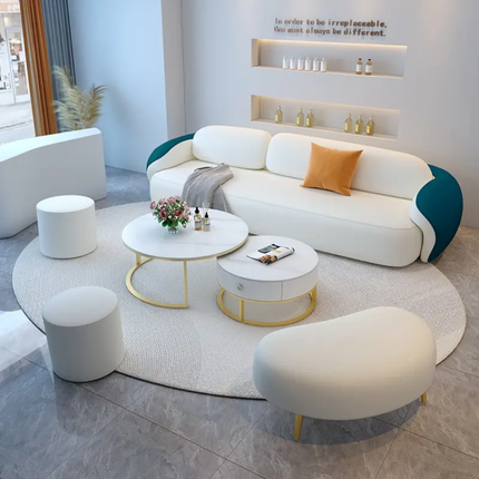 Modern living room with a white sofa, ottomans, and coffee tables.