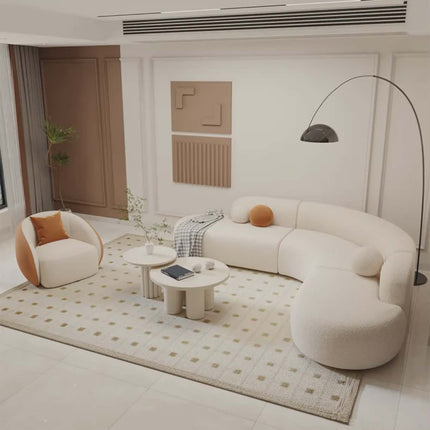 Modern living room with a curved white sofa, round coffee table, and decorative pillows.