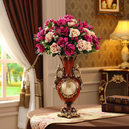 Decorative vase with pink and white flowers on a table in a room with a lamp and books.