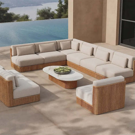 Outdoor patio furniture set with beige cushions and wooden frames on a patio with a view of water.