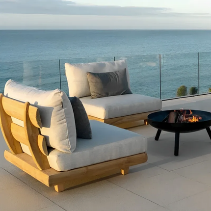 Outdoor patio furniture set with cushions by a fire pit overlooking the ocean.